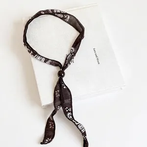 Collana in tessuto bohémien con perla in legno, ciondolo a cuore e nastro in seta