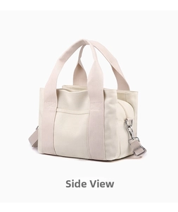 Detail view of off-white canvas tote bag with top zipper and adjustable shoulder strap