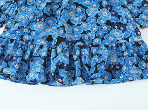 Detailaufnahme von blauem Blumen-Tintendruckstoff mit gestuften Rüschensaum-Details