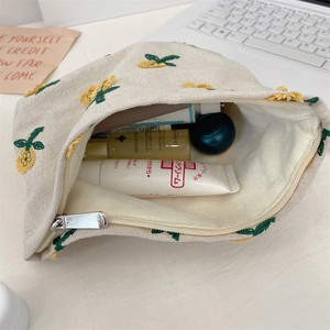 Détail d'une trousse à maquillage en toile brodée remplie de produits de soin