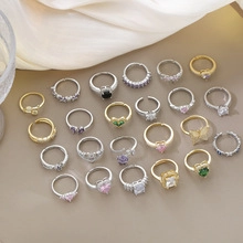 Flat lay of multiple mixed gold and silver rings with colorful faux gemstones and crystals