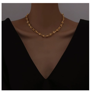 Detail of 18K gold knot chain necklace showing interlocking thorn link design on model