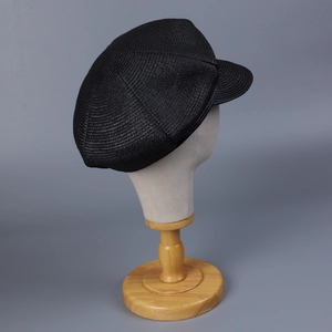 Detail view of black woven straw newsboy hat with refined texture on a mannequin