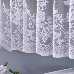 Detail of white lace dust cover showing intricate floral hollow patterns and scalloped edges
