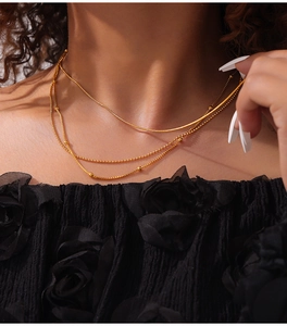 Detail of layered gold titanium steel necklaces featuring snake and bead chain designs