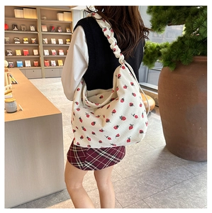 Detail of strawberry print corduroy bag with decorative twisted rope shoulder strap