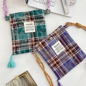 Close-up of retro plaid crossbody bags with tassels and woven straps in green and purple