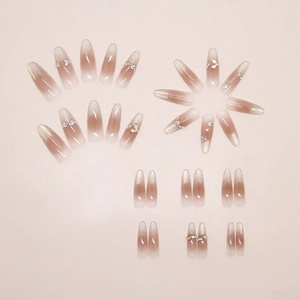 Detail of cat eye press-on nails with pearl accents and sparkling gradient stiletto shape