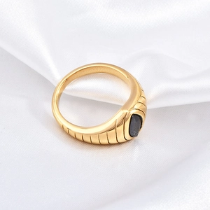 Detailed view of gold plated eye-shaped ring with black zircon on white silk