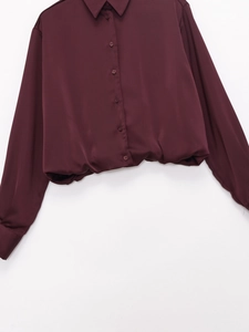 Detail of wine red satin shirt showing smooth silky texture and classic pointed collar