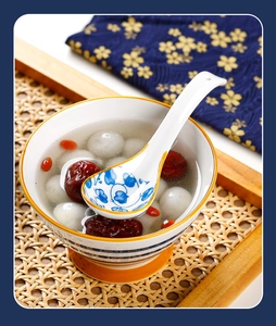 Detail view of blue floral ceramic spoon with thick curved handle and soup bowl