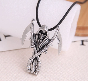 Macro shot of silver metal skull reaper pendant with crossed scythes on black rope chain