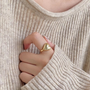 Polished golden heart-shaped 925 sterling silver ring worn with casual knitwear