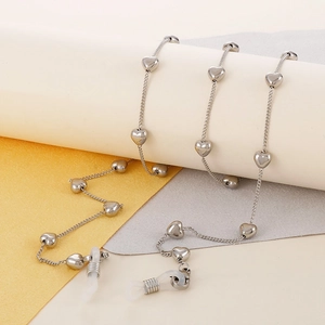 Detail of silver heart-shaped eyeglass chain with white anti-slip silicone loops on props