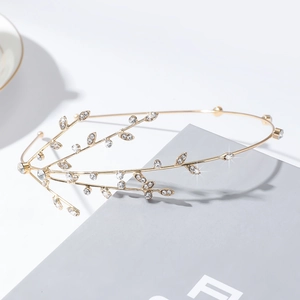 Detailed view of a golden rhinestone willow branch headband resting on a grey book