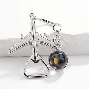 Silver airplane bottle opener keychain with a celestial planet glass ball pendant