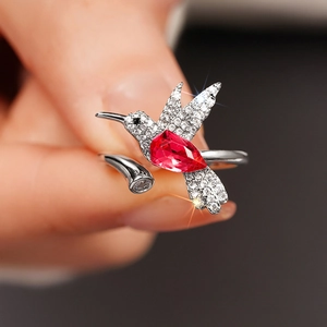 Detailopname van de kolibrie-ring met rode peervormige steen en glanzende kristallen
