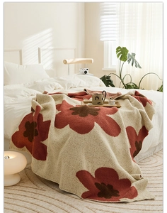 Close-up of a Nordic knitted throw blanket featuring large red and brown poppy patterns