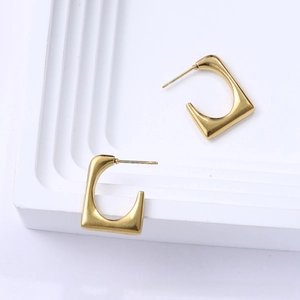 Close-up of minimalist gold titanium square hoop earrings on a clean white geometric base