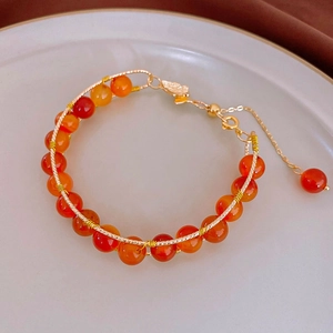 Close-up of vintage beaded bracelet with orange stones and golden wire wrapping detail