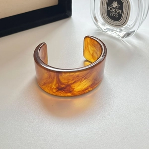 Detailansicht eines breiten Bernstein-Resin-Armreifs mit Schildpattmuster auf dem Tisch