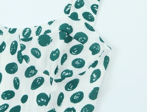 Close-up of neckline and strap on white dress with dark green polka dot print