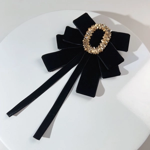 Elegant black velvet bow brooch with vintage gold crystal center on a white plate