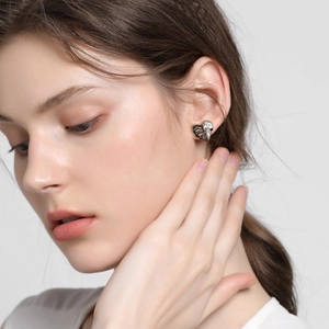 Gothic sterling silver skull hand stud earrings worn by model in a profile view