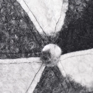 Detailed macro view of the black and white faux shearling texture on a plaid baseball cap