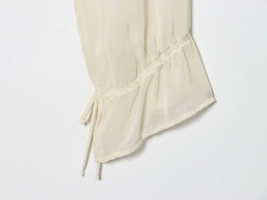 Detailed view of cream ruffled cuffs with elegant drawstring design on sheer fabric