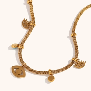Detail of gold mesh chain necklace featuring evil eye charms and blue enamel accents