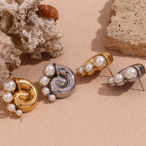Detailed view of spiral shell earrings in gold and silver finish with white pearls