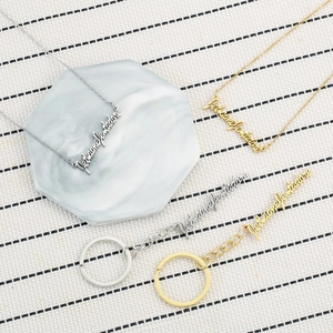 Golden and silver stainless steel Je t'aime necklaces and keychains on striped fabric
