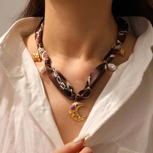 Détail du collier foulard en soie avec pendentifs lune et étoile dorés et gemmes colorées