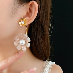 Close-up of elegant gold flower earrings with pearls and crystals on model's ear