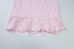 Détail de l'ourlet de la robe en dentelle rose avec texture fine et bord à volants