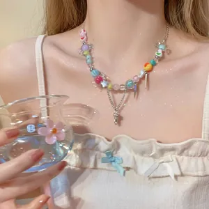 Détail d'un collier de perles colorées avec double chaîne argentée porté par un modèle