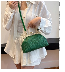 Detailed close-up of a green shell-shaped bag with floral embossing and crystal clasp