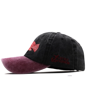 Close-up of vintage washed cotton baseball cap with anchor embroidery and red brim