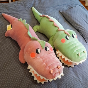 Cute pink and green plush crocodile pillows on a grey grid bedsheet for home decor