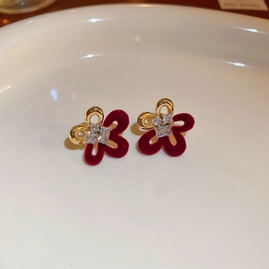 Detail of flower stud earrings with gold plating, dark red velvet texture, and zircons