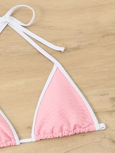 Macro detail of pink textured wavy fabric on triangle bikini top with white contrast piping