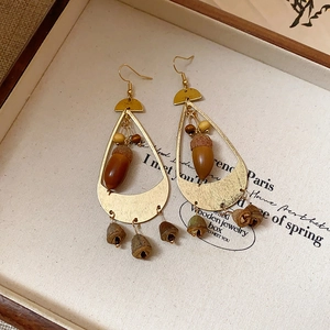 Detail of vintage teardrop earrings with acorn pendants in a rustic wooden jewelry box