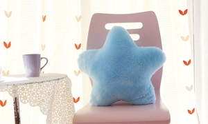 Detailed view of a soft blue star plush cushion placed on a cozy pink chair