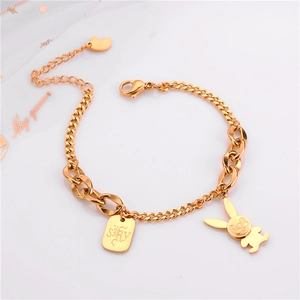 Detail showing a rose gold bunny charm and a rectangular tag on a stylish chain bracelet