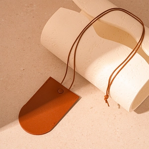 Detail shot of brown leather key holder necklace pendant on a textured stone surface