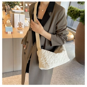 Close-up of beige quilted shoulder bag with diamond pattern on model in brown coat
