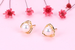 Close-up of golden triangular cutout earrings with white freshwater pearl insets