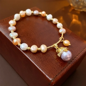 Détail du bracelet en perles multicolores avec pendentif chat sur un coffret en cuir