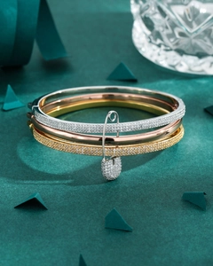 Macro detail of tricolor stacked bracelets with sparkling safety pin zircon pendant